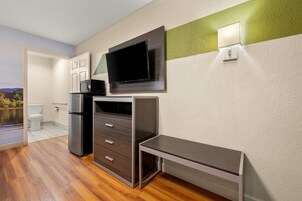 Una cocina moderna con microondas integrado, refrigerador y televisor de pantalla plana montado en la pared.