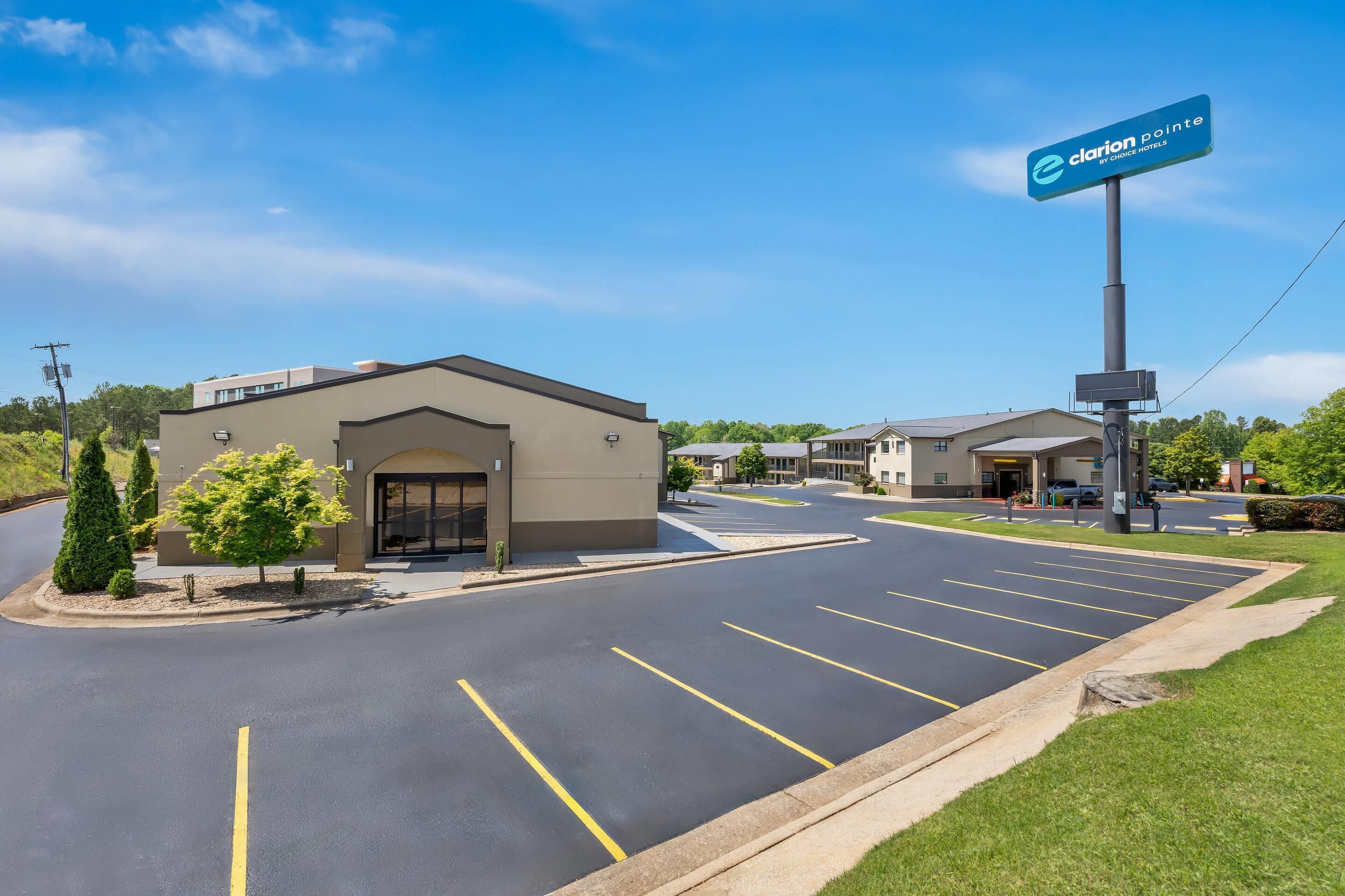 A hotel with a parking lot, a signboard, and a building entrance.