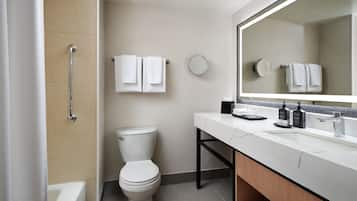 A modern bathroom with a bathtub, toilet, and vanity with a large mirror.