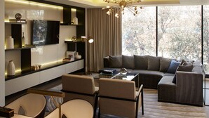 Una sala de estar moderna con un sofá, sillas, una mesa de centro y un televisor montado en la pared.