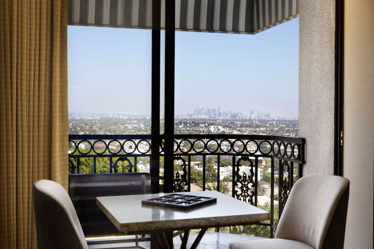 A balcony with a table and chairs, offering a view of a city skyline.