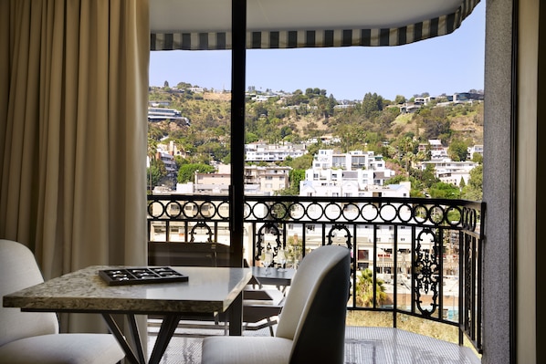 Un balcón con mesa y sillas, con vistas a una zona residencial con colinas y edificios.