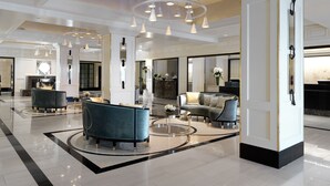 A spacious lobby with a grand chandelier, elegant seating, and a polished floor.