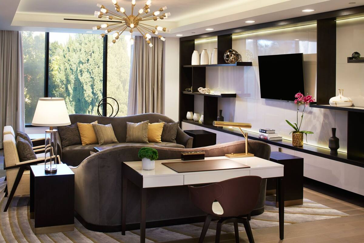 A modern living room with a sofa, a dining table, and a TV mounted on the wall.