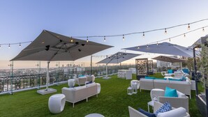 Terraza en la azotea con mobiliario exterior, sombrillas y luces colgantes.