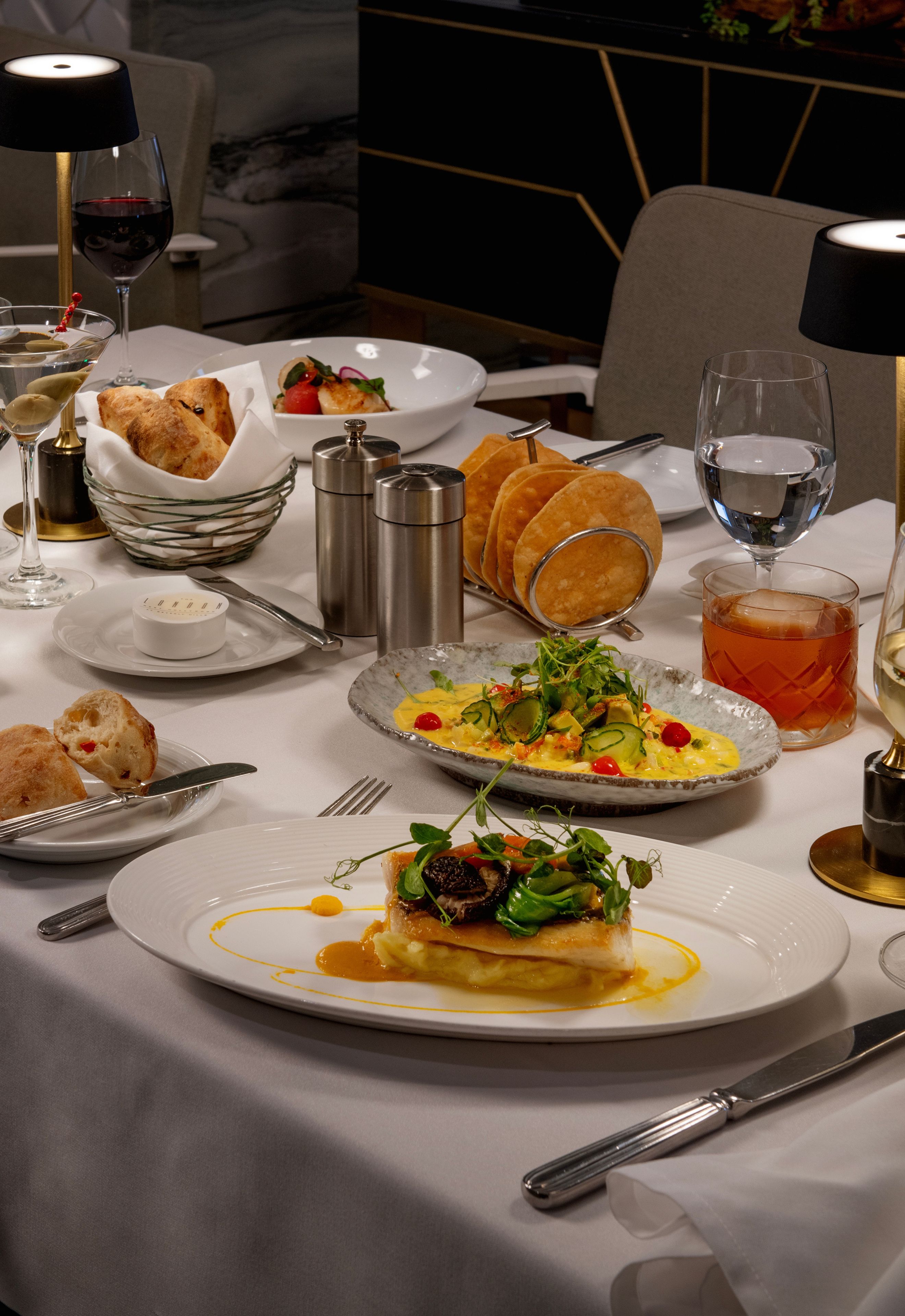A dining table set with various dishes, glasses, and cutlery, indicating a restaurant setting.
