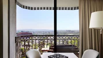 Un balcon avec une table et des chaises, une vue sur la ville et une lampe.