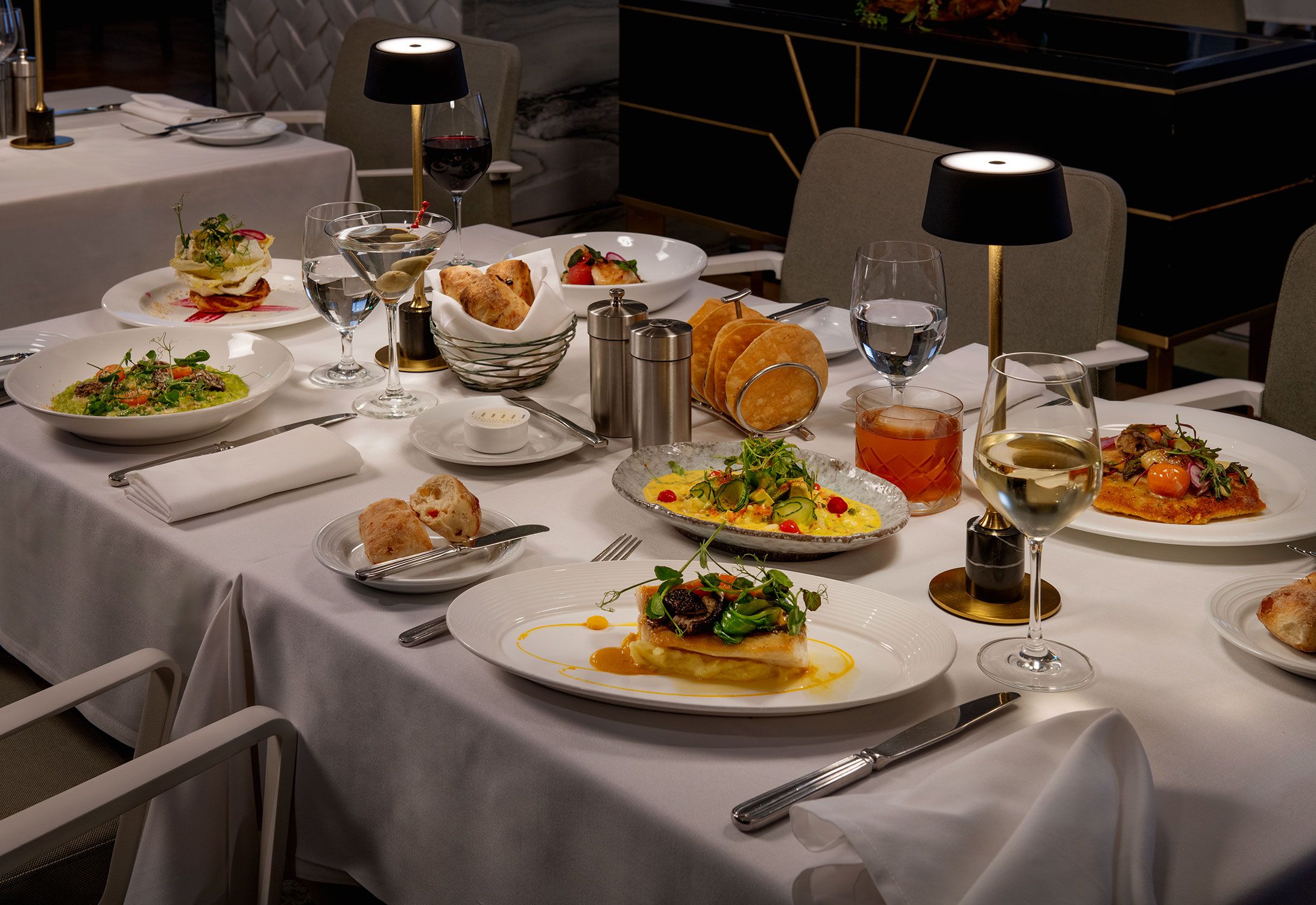 Une table à manger bien dressée, avec différents plats, verres et couverts, ce qui suggère qu’il s’agit d’un restaurant.