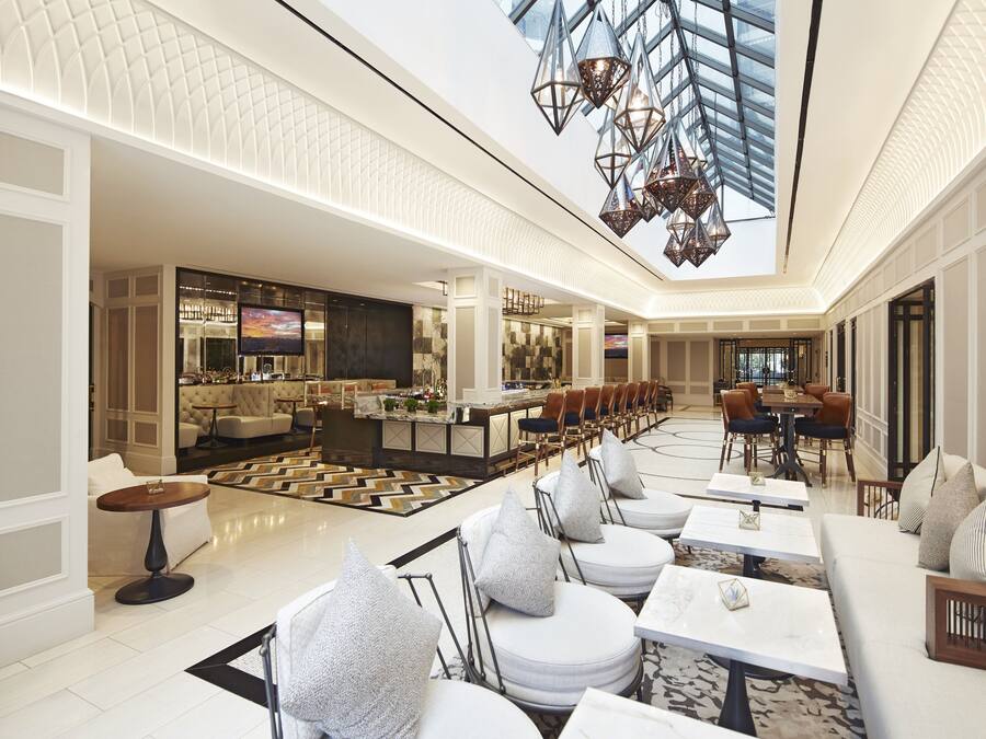 A spacious lobby with a high ceiling, a central bar area, and seating arrangements.