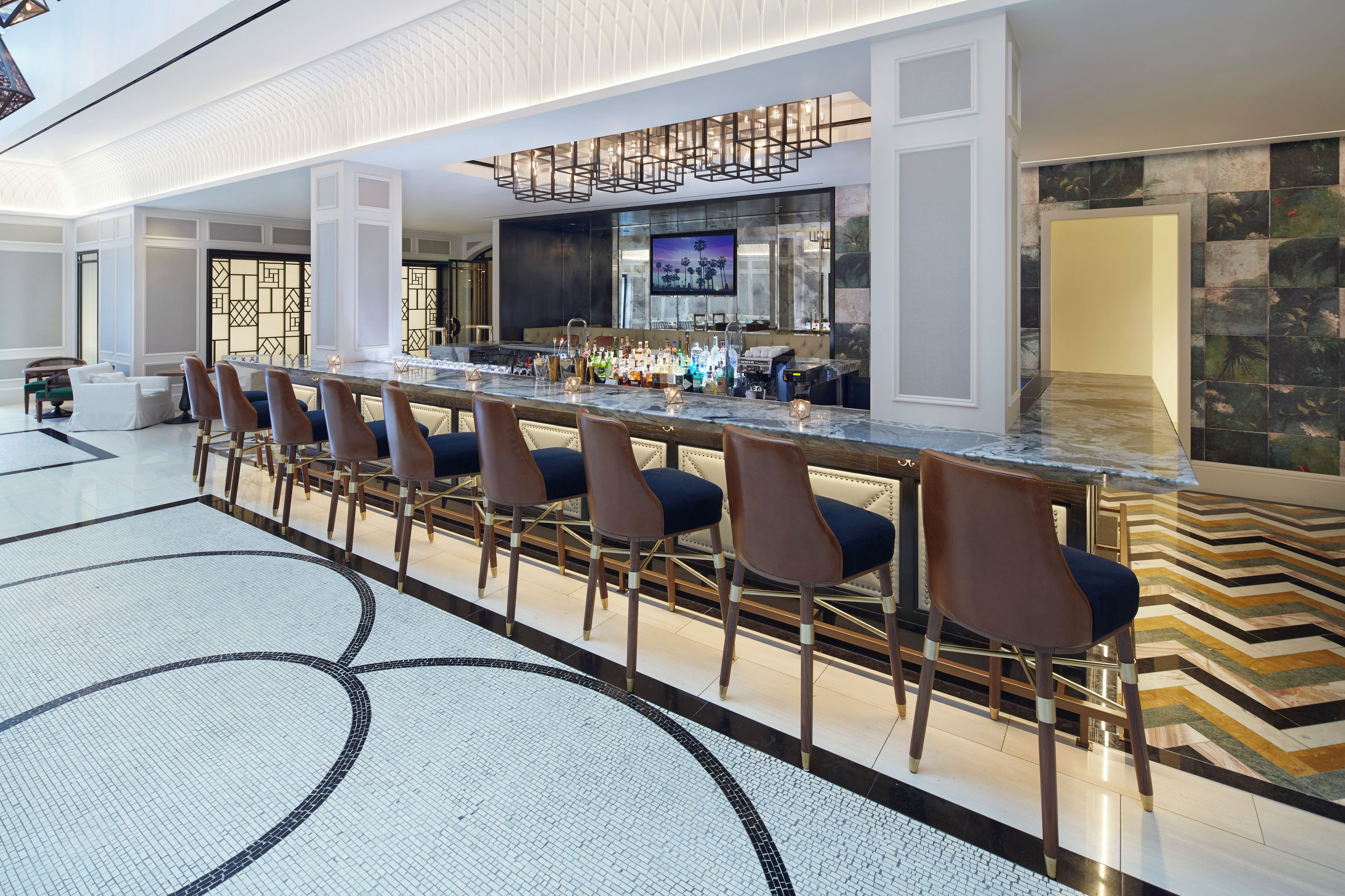 A bar area with a long counter, multiple bar stools, and a television screen.