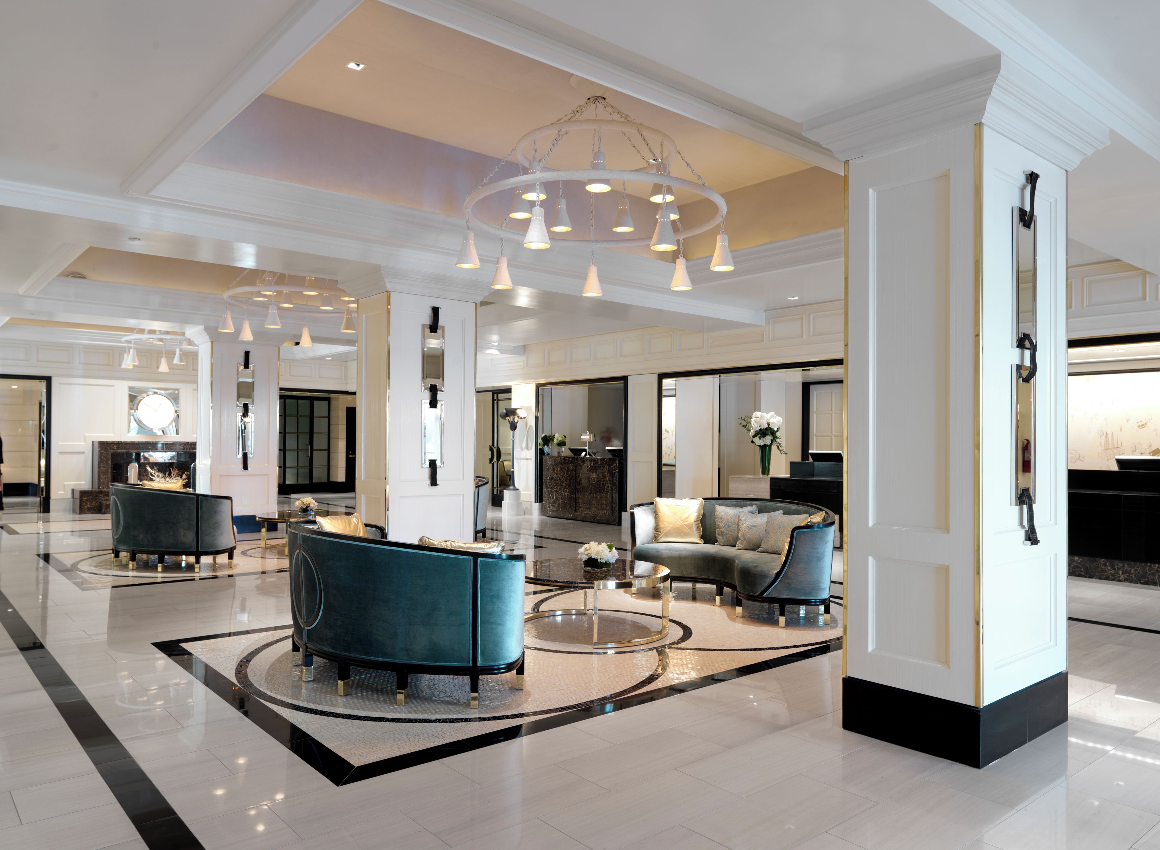 A spacious lobby with a grand chandelier, seating areas, and a piano.