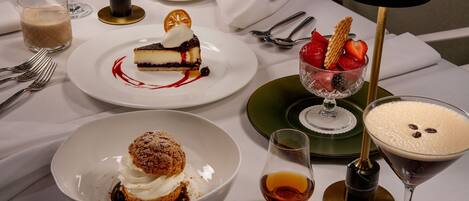 A table set with various desserts, a coffee cup, and a wine glass.