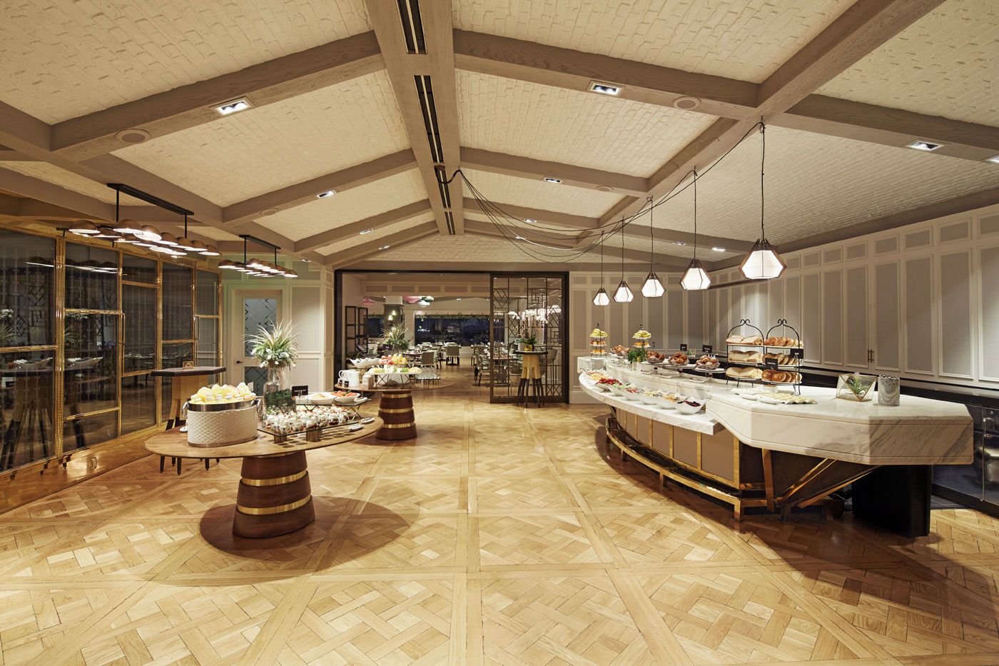 A spacious room with a high ceiling, wooden beams, and a buffet setup with various food items.