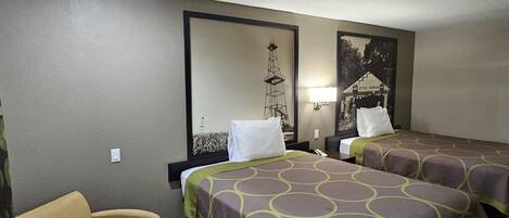 A hotel room with two beds, a chair, a lamp, and a wall mural.