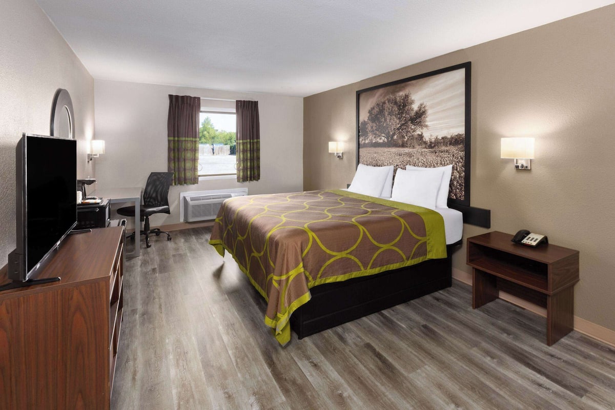 A hotel room with a bed, a desk with a computer, a television, and a telephone.