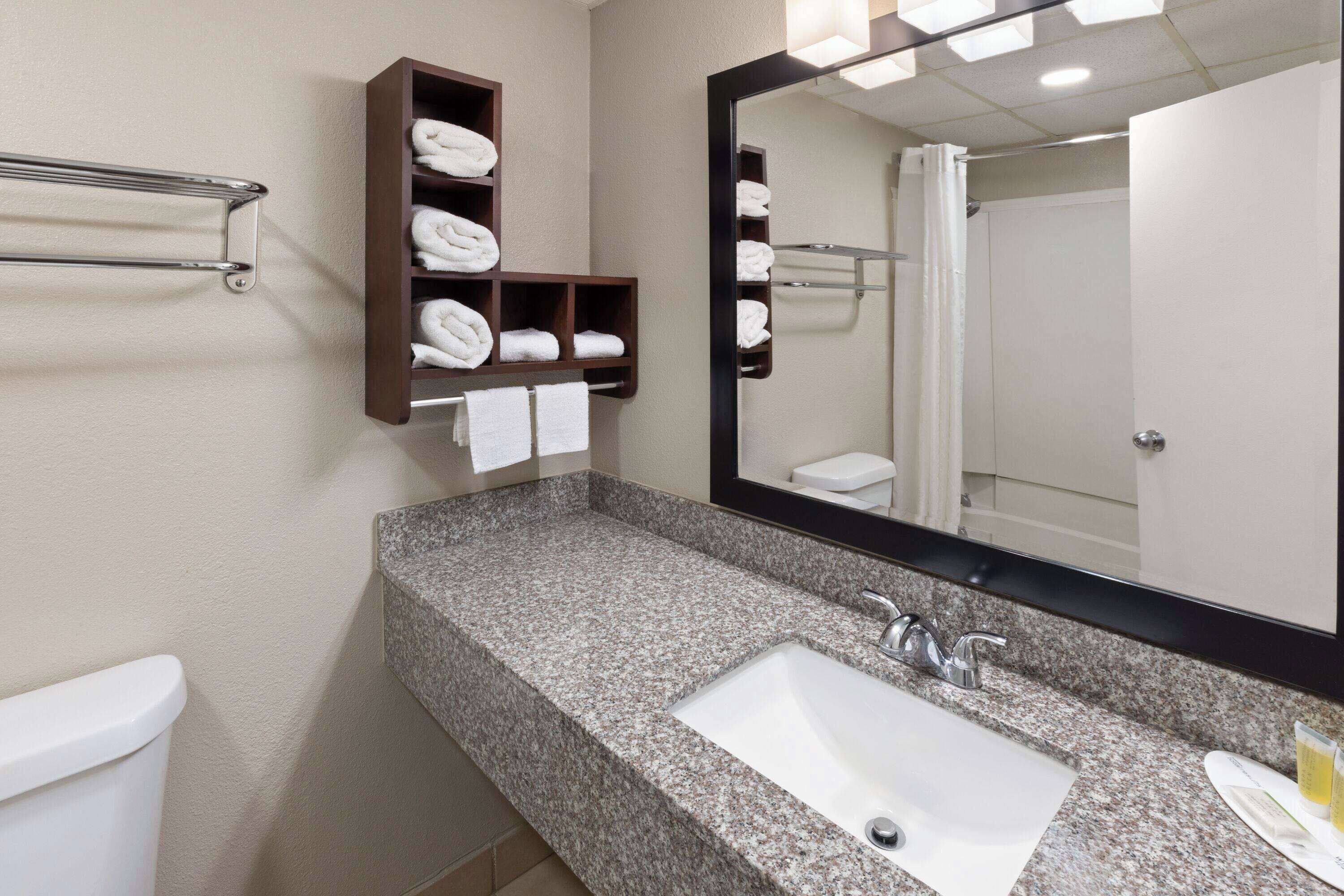 A bathroom with a granite countertop sink, a towel rack, and a mirror.