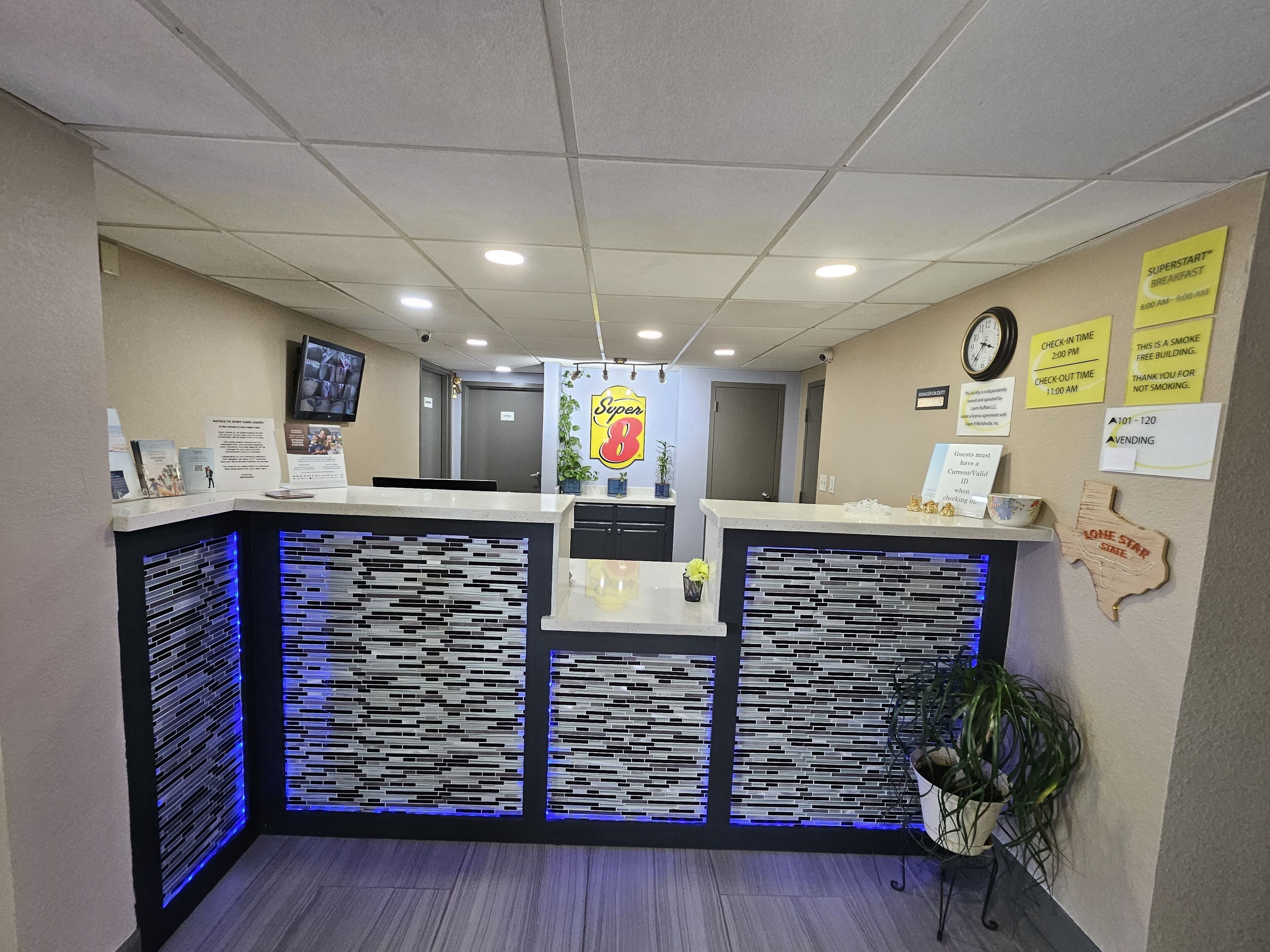 A reception area with a counter, a clock, and various informational signs.