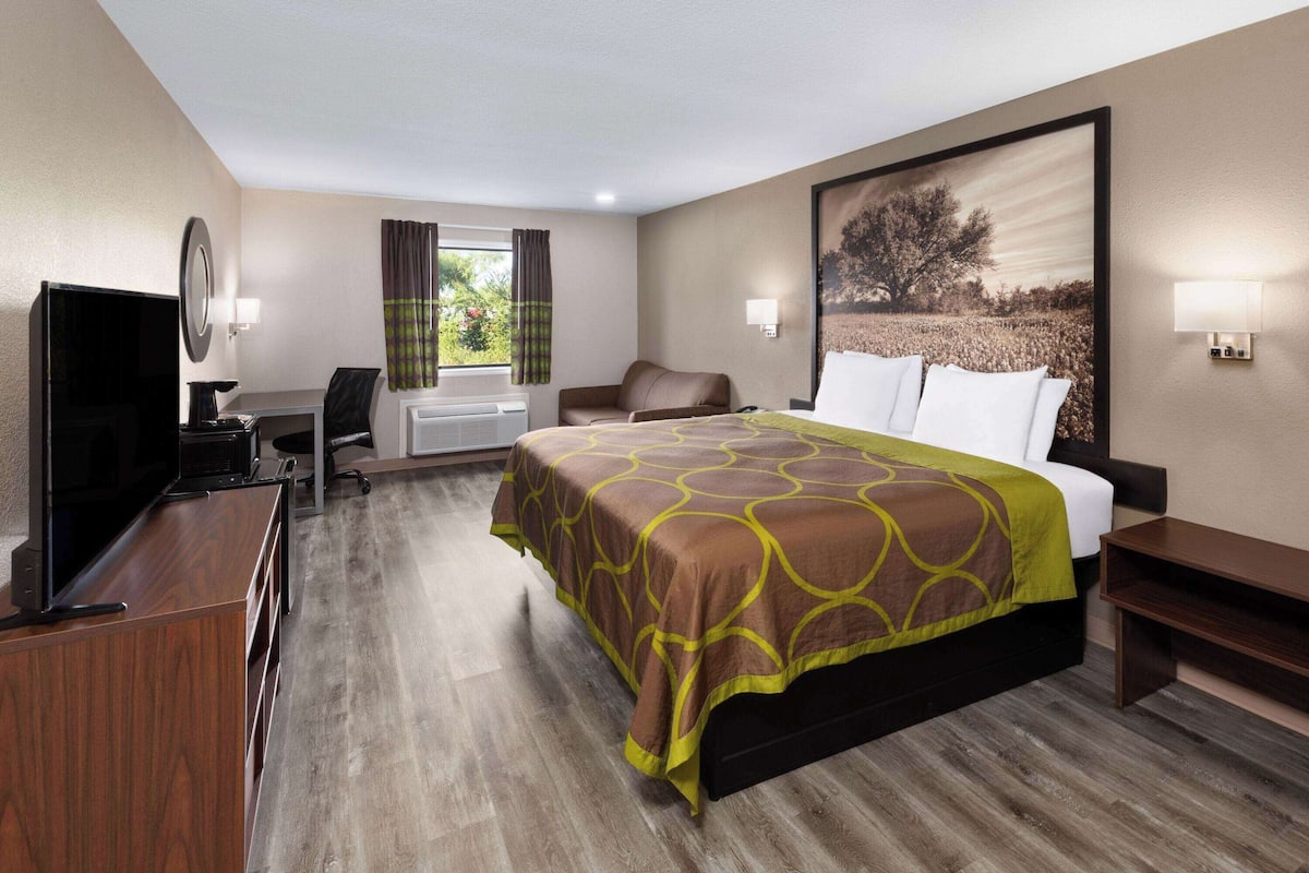 A hotel room with a bed, a desk, a chair, a television, and a window with curtains.