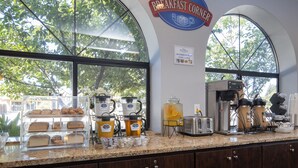 Una barra de desayuno con una máquina de café, tostadora y una vitrina con pasteles.