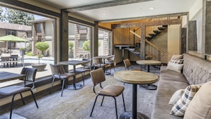 Un interior con una escalera de madera, un sofá y varias mesas y sillas.