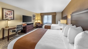 Habitación de hotel con una cama grande, un escritorio con silla, un televisor y una ventana con cortinas.