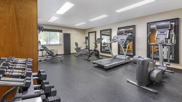 A gym with various exercise equipment, including treadmills, elliptical machines, and weight benches.