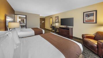 A hotel room with two beds, a desk, a chair, a television, and a framed picture on the wall.