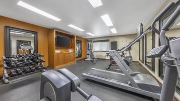 A gym with treadmills, weight machines, and dumbbells.