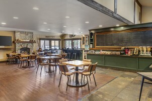 A restaurant with wooden tables and chairs, a stone fireplace, and a bar area with various items on display.