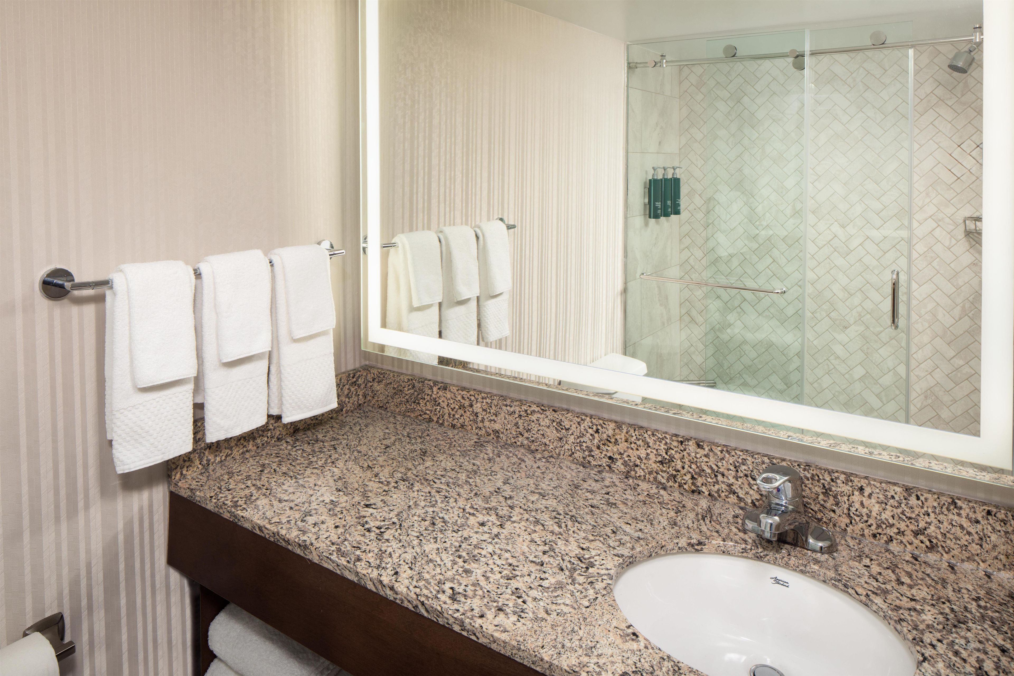 A bathroom with a granite countertop, a white sink, and a large mirror.