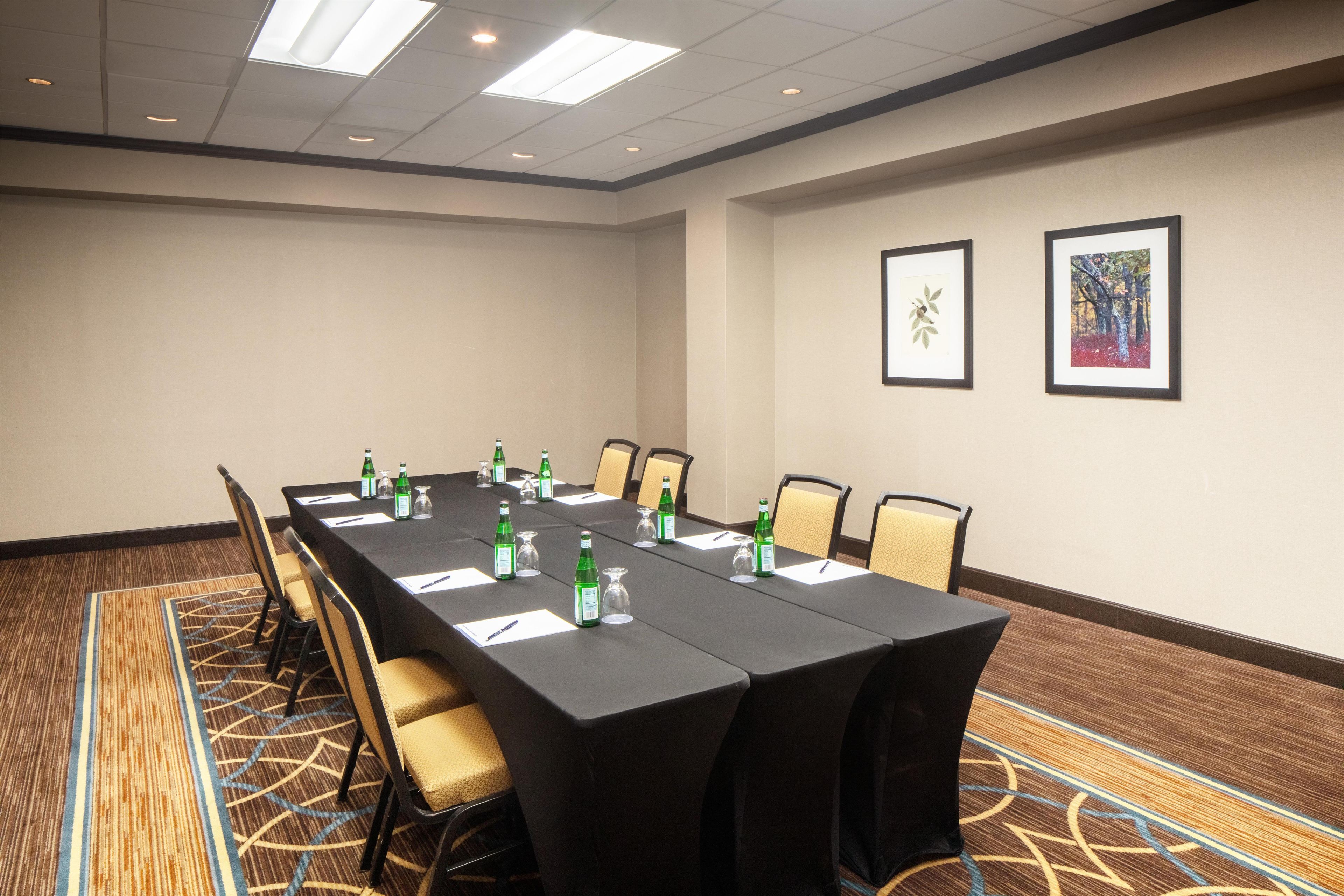 A conference room with a long table, chairs, and framed pictures on the wall.