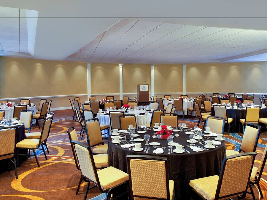 A conference room with round tables, chairs, and a podium.