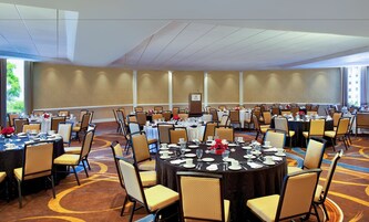Un salón de conferencias con mesas redondas, sillas y un atril.