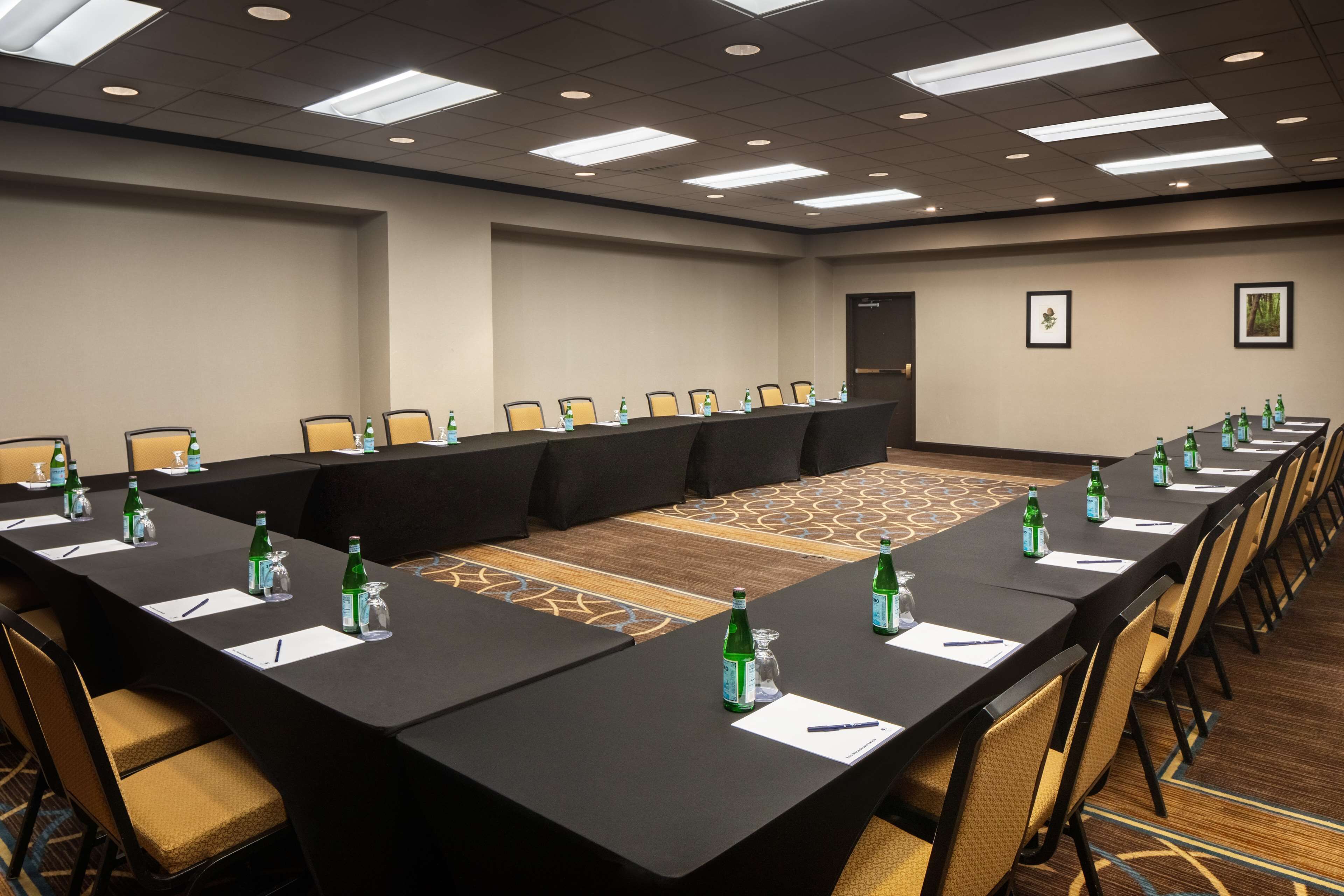 Une salle de conférence avec une longue table, des chaises, des bouteilles d’eau et des plaques nominatives.