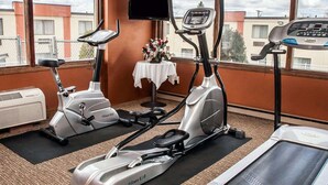 Un gimnasio con dos bicicletas estáticas, una cinta de correr y una pantalla de televisión.