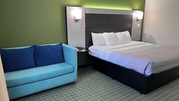 A hotel room with a bed, a blue sofa, and two wall-mounted lights.