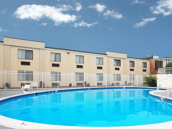 Guests can enjoy a refreshing swim in the hotel's pool, surrounded by rooms with balconies and windows.