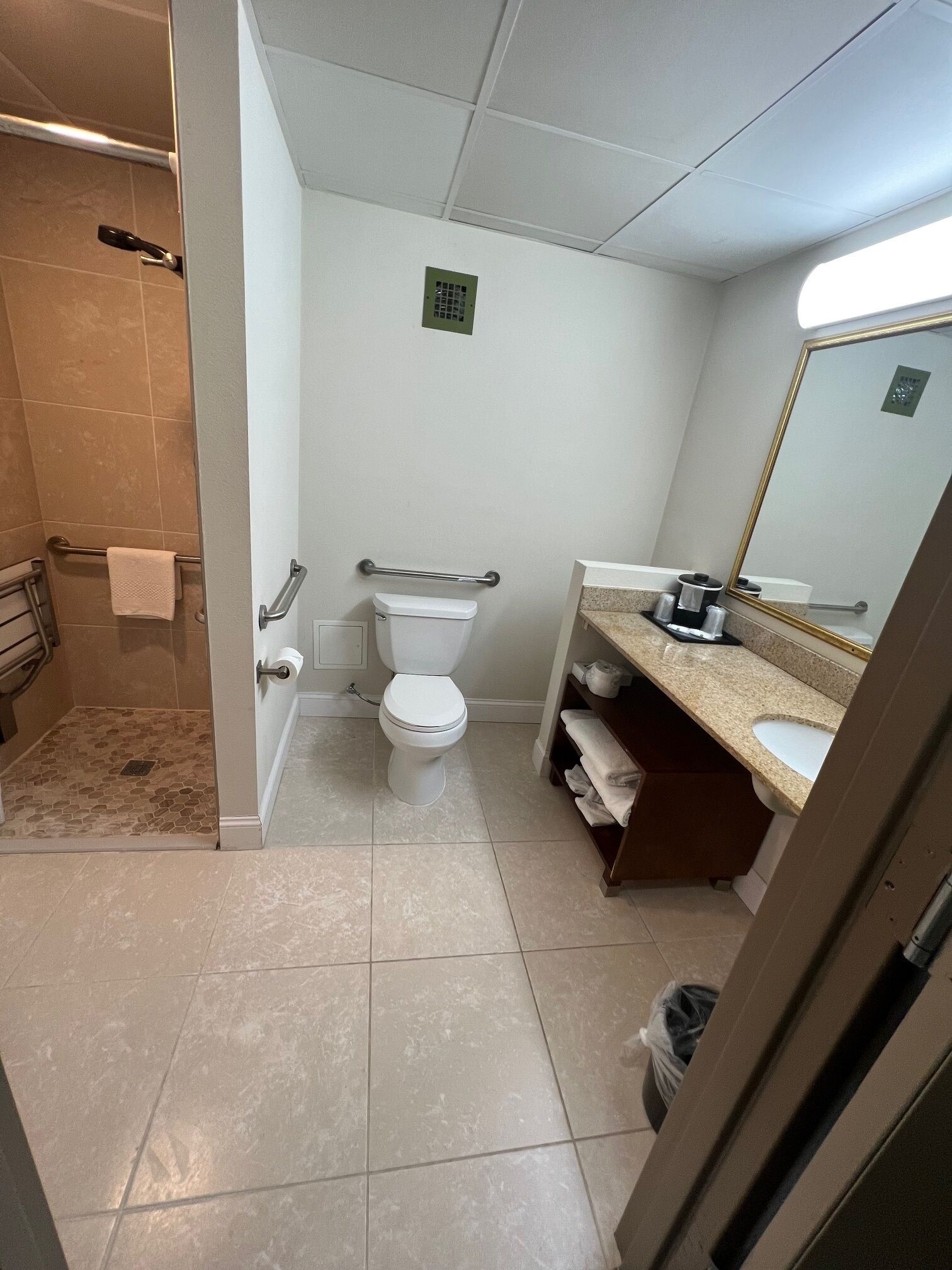 Ein Badezimmer mit Toilette, Duschbereich, Waschbecken und Spiegel.