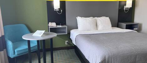 A hotel room with a bed, bedside tables, a small round table with a chair, and a telephone.