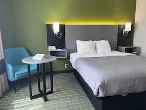 A hotel room with a bed, bedside tables, a small round table with a chair, and a telephone. - Quality Inn Seekonk - Providence (Seekonk)