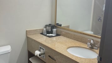 Une salle de bain avec des toilettes blanches, un lavabo avec un miroir et un espace douche.