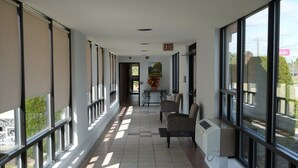 Un pasillo largo, bien iluminado, con amplios ventanales a ambos lados, que conduce a una salida.