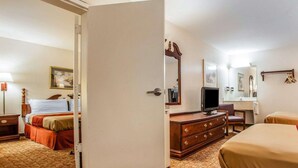 A hotel room with a bed, a dresser, a television, a desk, and a chair. - Econo Lodge Douglassville - Pottstown (Douglassville)