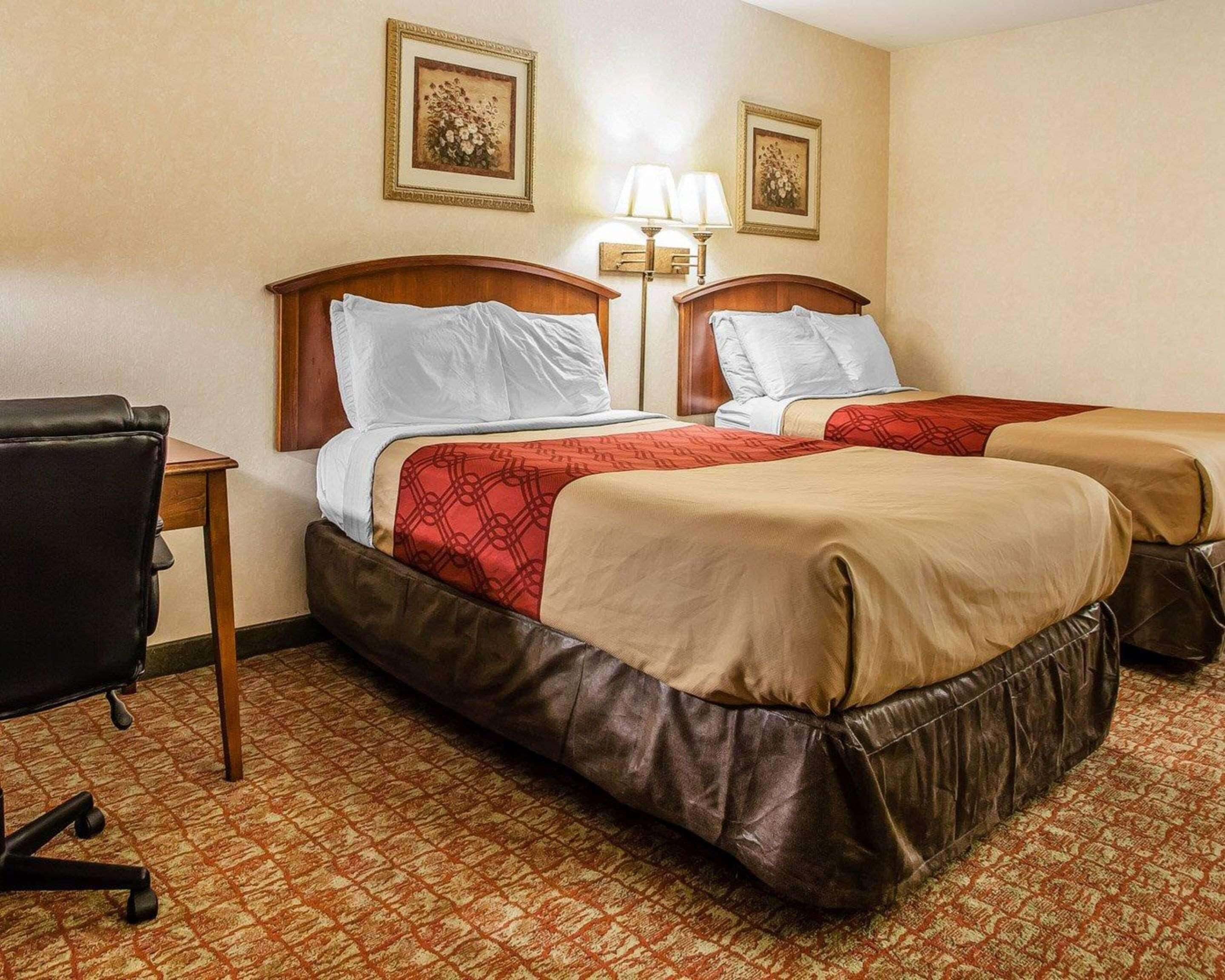 A hotel room with two beds, a desk, and a chair.