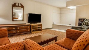 A hotel room with a TV, a wooden dresser, a sofa, and a bathtub. - Econo Lodge Douglassville - Pottstown (Douglassville)