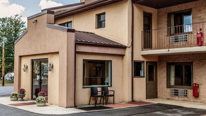 A two-story building with a flat roof, a balcony on the upper floor, and a small outdoor seating area with chairs and tables. - Econo Lodge Douglassville - Pottstown (Douglassville)