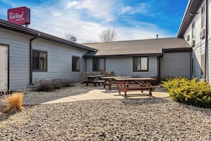 A Red Roof Inn & Suites with a patio area, outdoor seating, and a gravel ground cover.