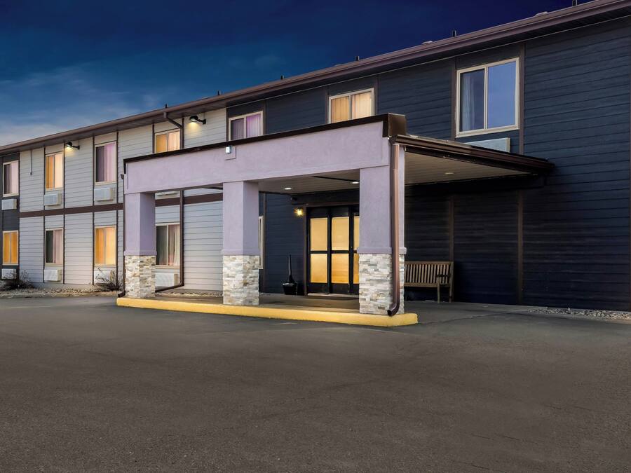 Un hôtel à plusieurs étages doté d’une entrée couverte, de climatiseurs et d’un banc à l’extérieur.