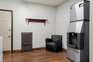 A room with a door, a chair, a refrigerator, and a shelf. - Red Roof Inn & Suites Tomah (Tomah)