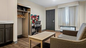 A hotel room with a kitchenette, a dining table, a sofa, a door, and a window with curtains. - Red Roof Inn & Suites Tomah (Tomah)